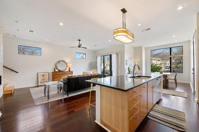 kitchen with dark wood-style flooring, a sink, dishwasher, and light brown cabinetry