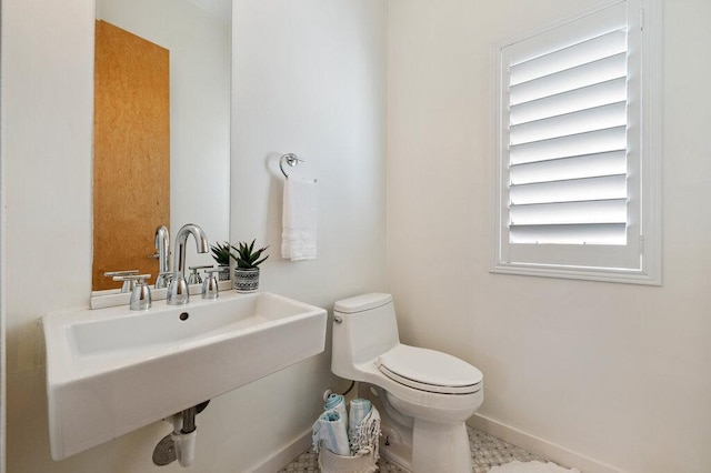 bathroom featuring toilet, baseboards, and a sink