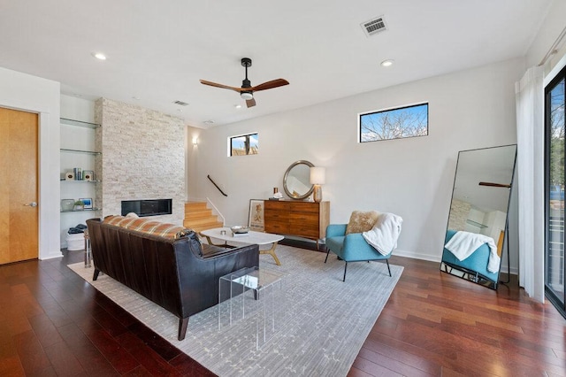 living room with recessed lighting, visible vents, a stone fireplace, and hardwood / wood-style floors