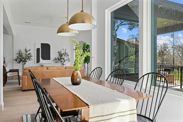 dining space with a wealth of natural light, visible vents, and wood finished floors