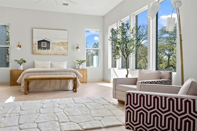 bedroom with multiple windows, wood finished floors, visible vents, and baseboards