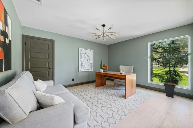 office area with light wood-style floors, baseboards, and an inviting chandelier