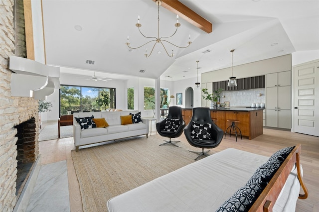 living room with arched walkways, beamed ceiling, light wood-style floors, a fireplace, and high vaulted ceiling