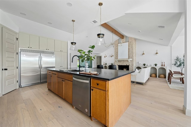 kitchen with visible vents, dark countertops, light wood-style flooring, stainless steel appliances, and a sink