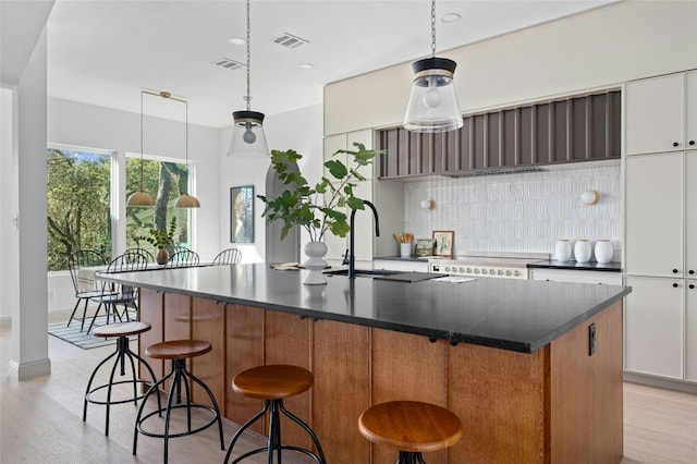 kitchen featuring tasteful backsplash, dark countertops, and visible vents