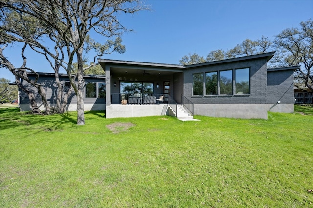 rear view of property featuring a yard and brick siding