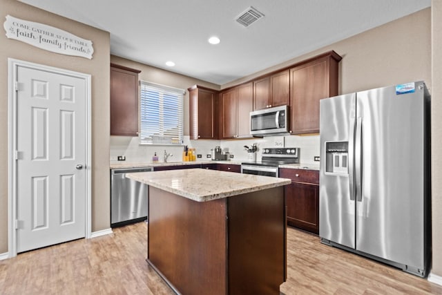 kitchen featuring light wood-type flooring, visible vents, stainless steel appliances, and a center island