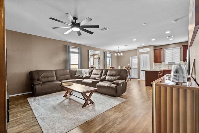 living room with light wood finished floors, visible vents, and a ceiling fan