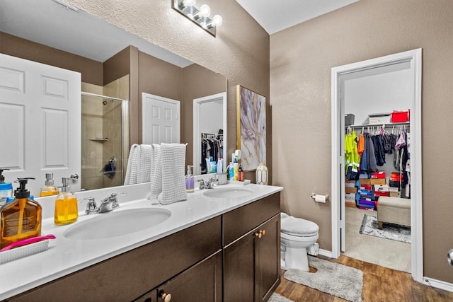 full bath with a sink, a shower stall, toilet, and wood finished floors