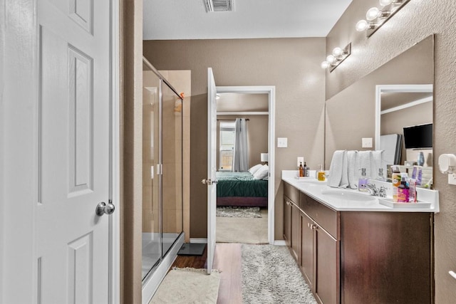 ensuite bathroom featuring visible vents, connected bathroom, a shower stall, vanity, and wood finished floors