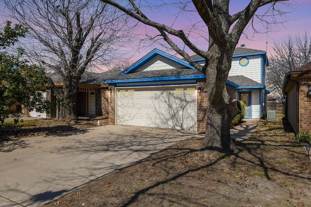 view of front facade featuring a garage, central AC, concrete driveway, and brick siding