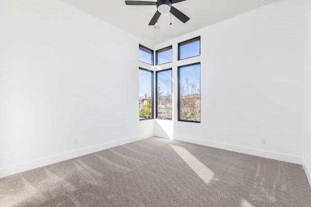 carpeted spare room featuring ceiling fan and baseboards