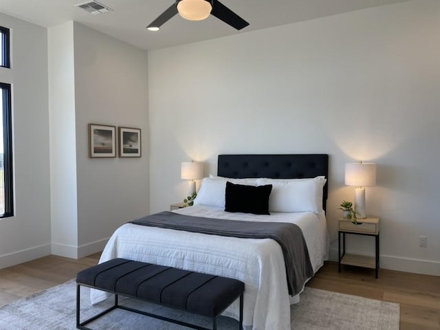 bedroom with light wood finished floors, a ceiling fan, visible vents, and baseboards