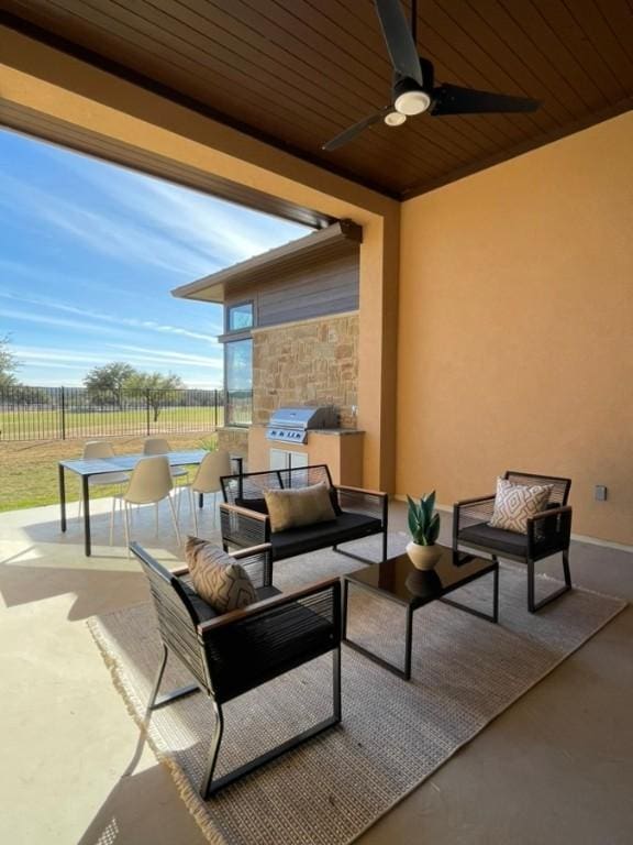 view of patio featuring ceiling fan, area for grilling, fence, and an outdoor living space