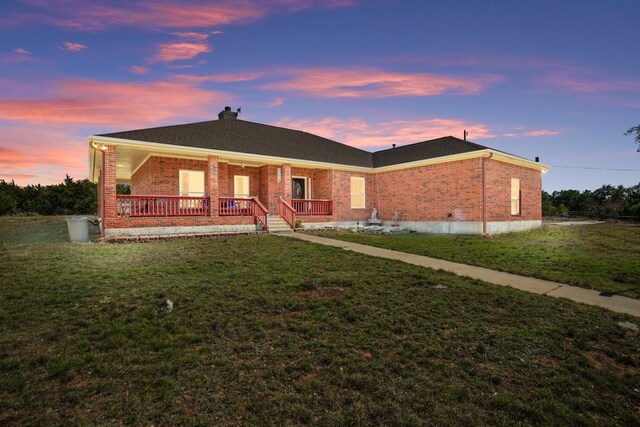 3660 Stagecoach Ranch Loop, Dripping Springs, TX 78620 - back of property at dusk featuring roof with shingles, a yard, brick siding, and a porch