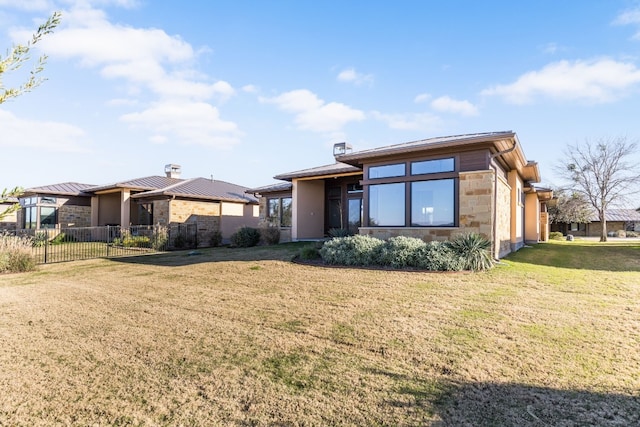 view of front of property with stone siding, a chimney, fence, and a front lawn