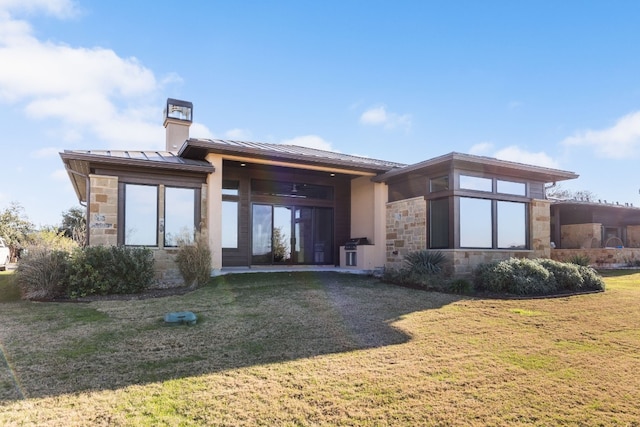 rear view of house with metal roof, stone siding, a yard, and a standing seam roof