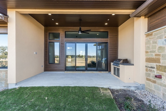 entrance to property featuring stucco siding, stone siding, an outdoor kitchen, and a patio