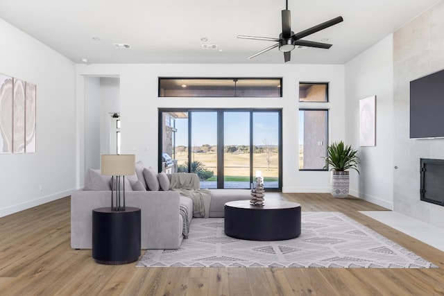 living area featuring baseboards, a tiled fireplace, and wood finished floors