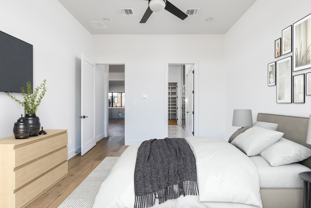 bedroom with a ceiling fan, baseboards, visible vents, and light wood finished floors