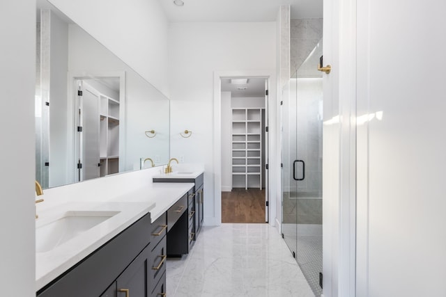 full bathroom featuring marble finish floor, a shower stall, a walk in closet, and a sink