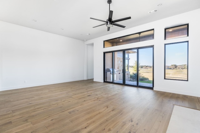 unfurnished room featuring ceiling fan, wood finished floors, visible vents, and baseboards