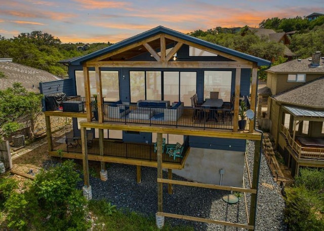 back of house at dusk featuring a deck