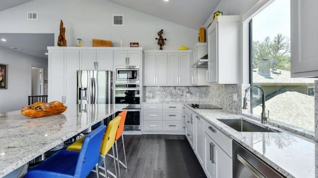 kitchen with visible vents, lofted ceiling, appliances with stainless steel finishes, a breakfast bar, and a sink