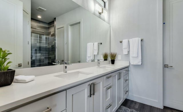 bathroom with visible vents, a sink, a shower stall, and double vanity