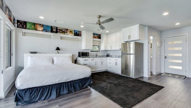 bedroom with a sink, recessed lighting, wood finished floors, and freestanding refrigerator