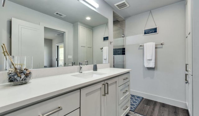 full bathroom with wood finished floors, vanity, visible vents, and baseboards