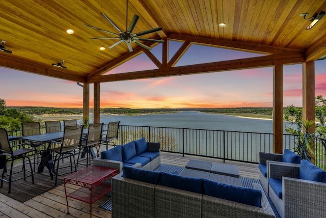 deck at dusk featuring a water view, ceiling fan, and an outdoor hangout area