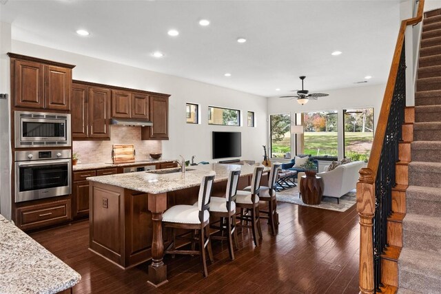 kitchen with recessed lighting, a sink, open floor plan, and stainless steel appliances