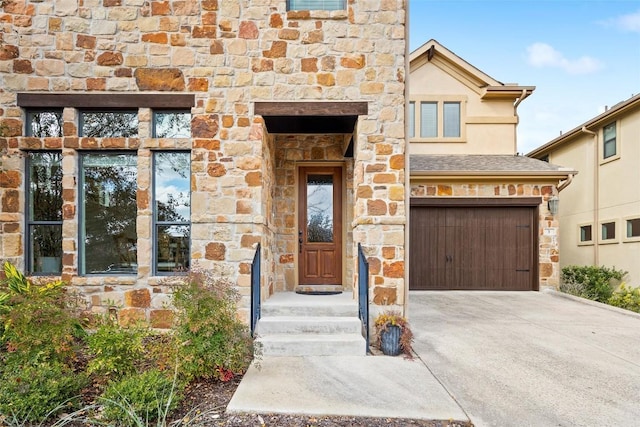 doorway to property featuring a garage, driveway, and stone siding