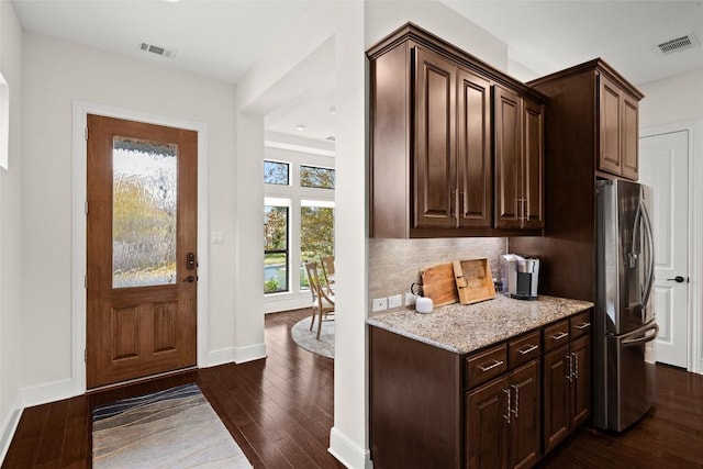 interior space with stainless steel fridge, baseboards, tasteful backsplash, visible vents, and dark wood-style floors