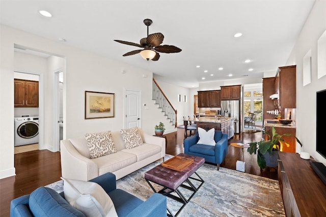 living area featuring baseboards, washer / clothes dryer, dark wood-style floors, stairway, and a ceiling fan