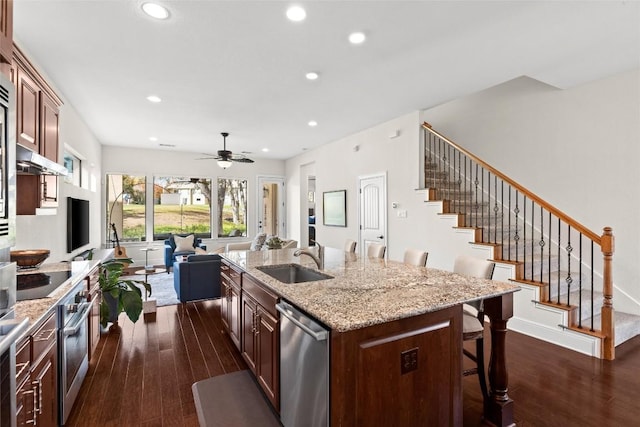 kitchen with dishwasher, dark wood-style floors, a kitchen bar, a sink, and recessed lighting