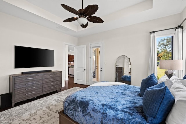 bedroom featuring ceiling fan, visible vents, dark wood-style floors, and a raised ceiling