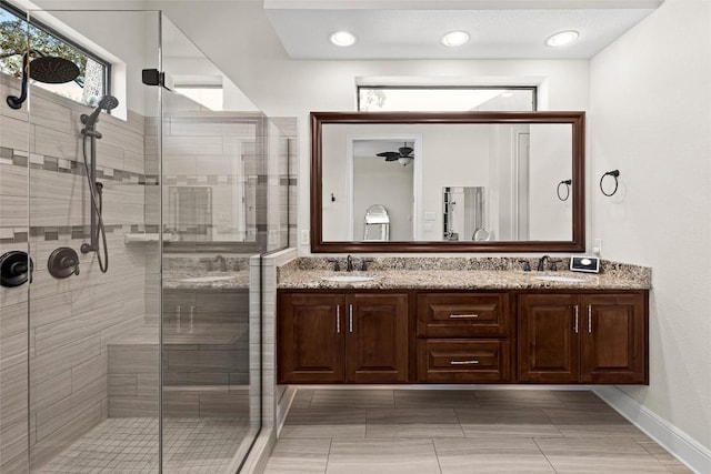full bath featuring double vanity, baseboards, a sink, and a stall shower