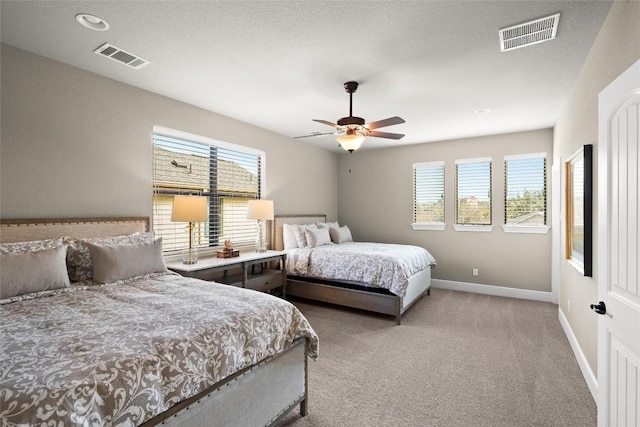 bedroom featuring visible vents, a ceiling fan, baseboards, and light colored carpet