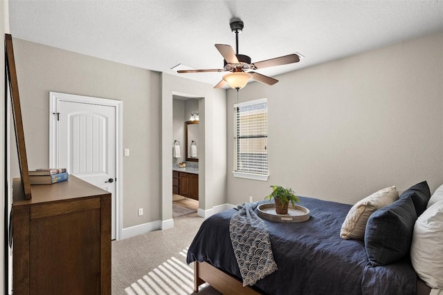 bedroom featuring baseboards, a ceiling fan, light colored carpet, ensuite bath, and a textured ceiling