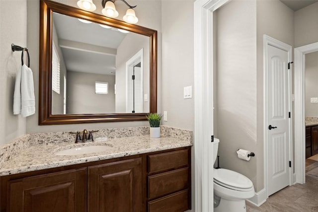 bathroom with toilet, baseboards, and vanity