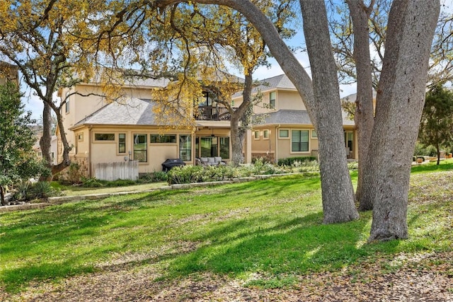 traditional home featuring a front lawn, a balcony, and stucco siding