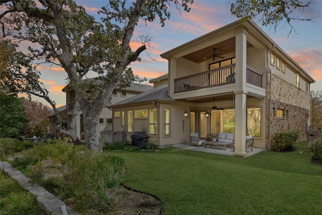 back of property with ceiling fan, an outdoor living space, a patio area, a balcony, and a yard