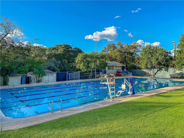 community pool featuring a patio area, fence, and a lawn