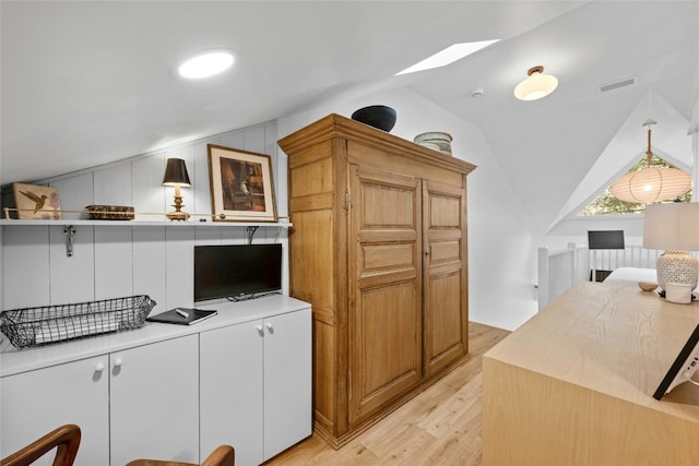 kitchen featuring light wood-type flooring, vaulted ceiling with skylight, light countertops, and visible vents