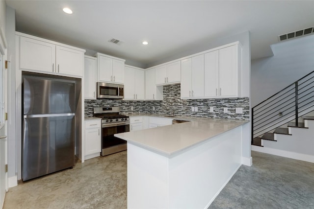 6902 Carver Ave Unit B, Austin, TX 78752 - kitchen featuring stainless steel appliances, a peninsula, white cabinets, backsplash, and light countertops