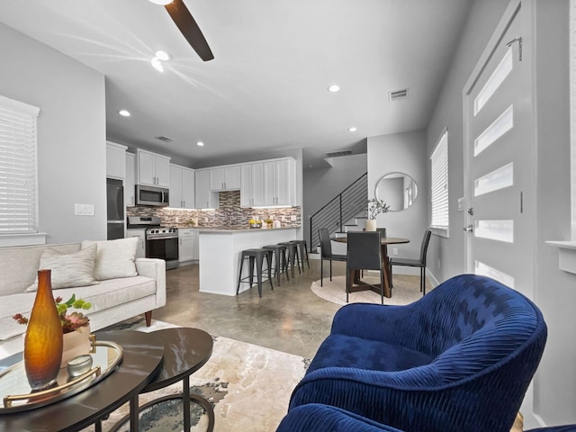 living area featuring recessed lighting, visible vents, finished concrete floors, baseboards, and stairs