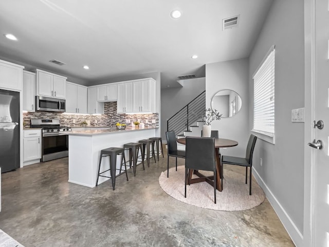 6902 Carver Ave Unit B, Austin, TX 78752 - kitchen with appliances with stainless steel finishes, finished concrete flooring, tasteful backsplash, white cabinets, and recessed lighting