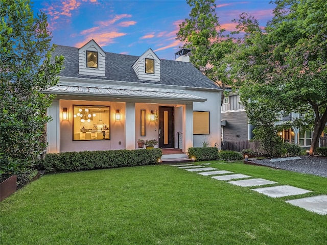 view of front of home with a shingled roof, covered porch, a front lawn, and stucco siding